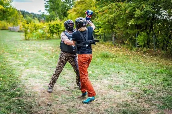 Zwei Personen in Schutzausrüstung üben einen Nahkampf auf einer Wiese