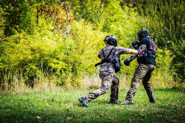 Zwei Personen in Schutzausrüstung üben einen Nahkampf im Freien