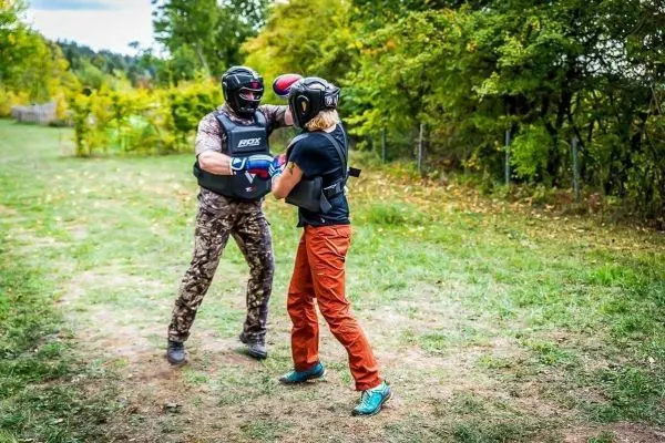 Zwei Personen in Schutzausrüstung üben Kampftechniken auf einer Wiese