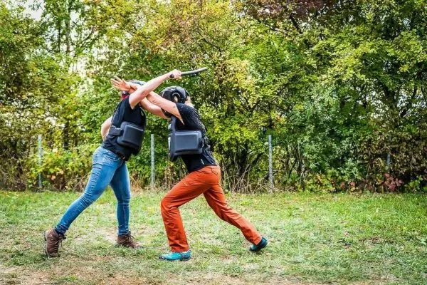 Zwei Personen in Schutzwesten führen einen Trainingskampf mit einem Stock durch
