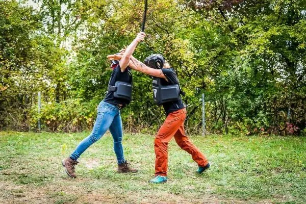 Zwei Personen mit Schutzausrüstung führen einen Übungskampf mit einem Stock durch