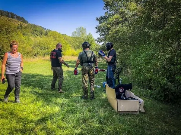 Drei Personen in Schutzausrüstung bereiten sich auf eine Trainingseinheit im Freien vor