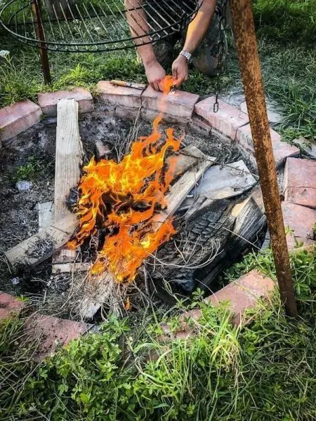 Person legt Holz in ein Feuer im Steinkreis