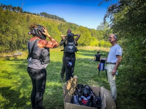 Person setzt Kopfhörer auf, während andere Personen im Hintergrund stehen