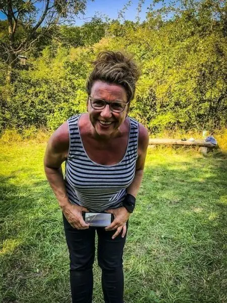 Person steht auf einer Wiese und hält ein Smartphone in der Hand
