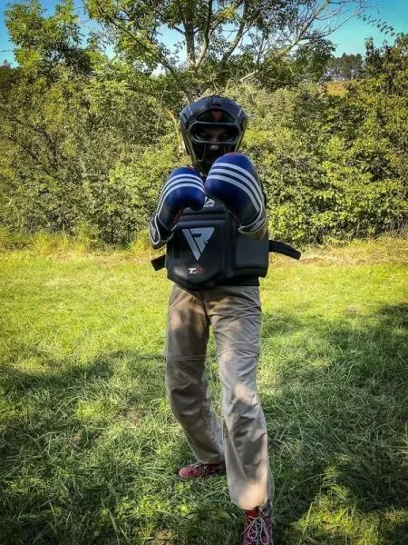 Person steht im Gras und hält Boxhandschuhe bereit