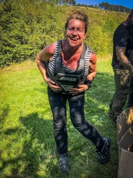 Person trägt eine Gewichtswesten und lächelt auf einer Wiese