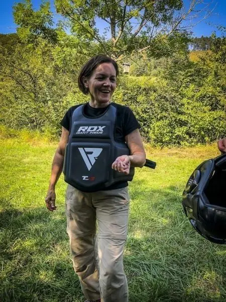 Person trägt eine Schutzweste und interagiert mit einer anderen Person im Freien