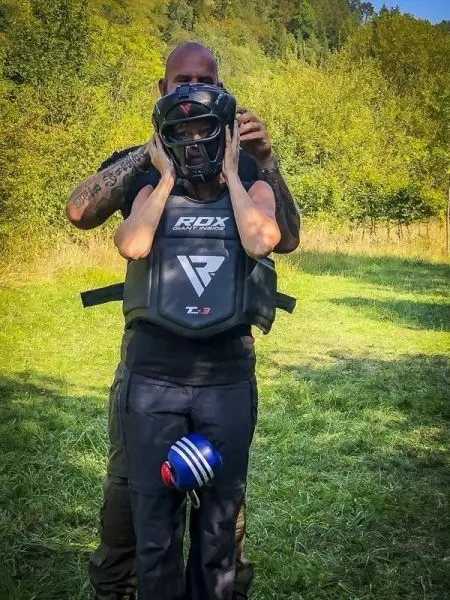 Person trägt Schutzausrüstung, während eine andere Person den Helm anpasst