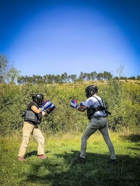 Zwei Kämpfer in Schutzausrüstung führen ein Boxtraining im Freien durch
