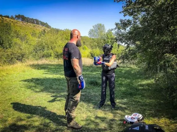 Zwei Personen in Boxhandschuhen stehen auf einer Wiese und bereiten sich auf das Training vor
