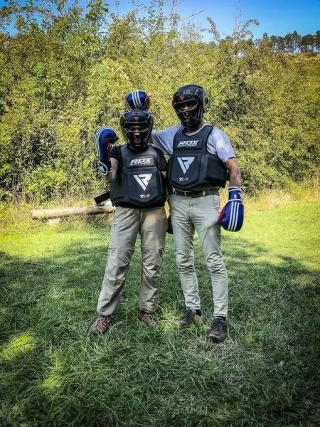 Zwei Personen in Schutzausrüstung stehen auf einer Wiese und posieren