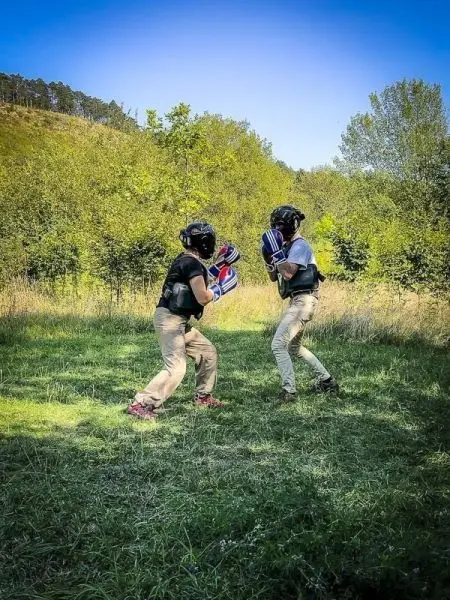 Zwei Personen in Schutzausrüstung üben im Freien Boxtechniken