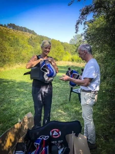 Zwei Personen stehen auf einer Wiese und halten Schutzhelme in den Händen