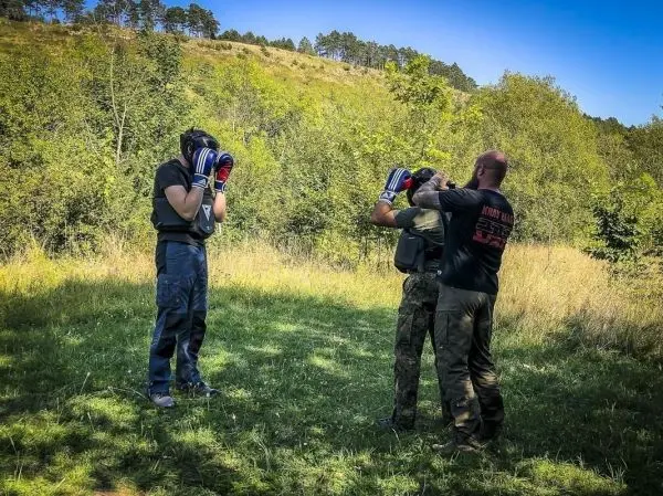 Zwei Personen tragen Boxhandschuhe und üben in einer grünen Wiese