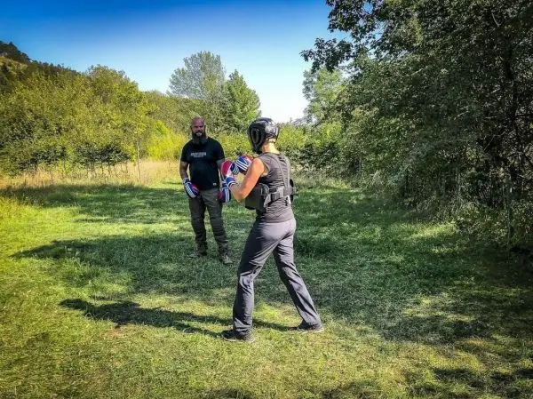 Zwei Personen trainieren im Freien mit Boxhandschuhen und Schutzausrüstung