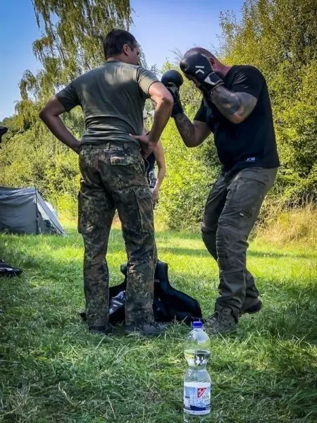 Zwei Personen üben Boxtechniken, eine Person trägt Boxhandschuhe