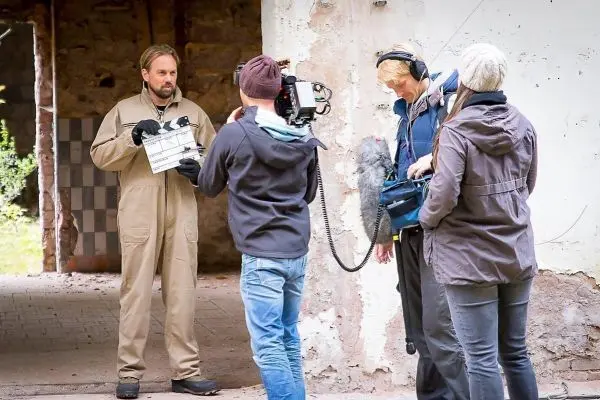 Drehteam bereitet Aufnahme mit Kamera und Klappe in einem alten Gebäude vor