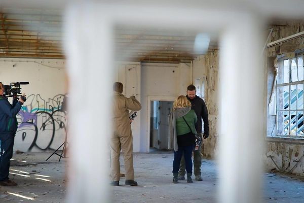 Drei Personen stehen in einem leerstehenden Raum mit Graffiti an den Wänden