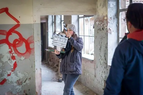 Frau hält Klappe in einem verlassenen Gebäude mit beschädigten Wänden