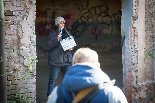 Frau hält Klappe vor einer verfallenen Wand mit Graffiti