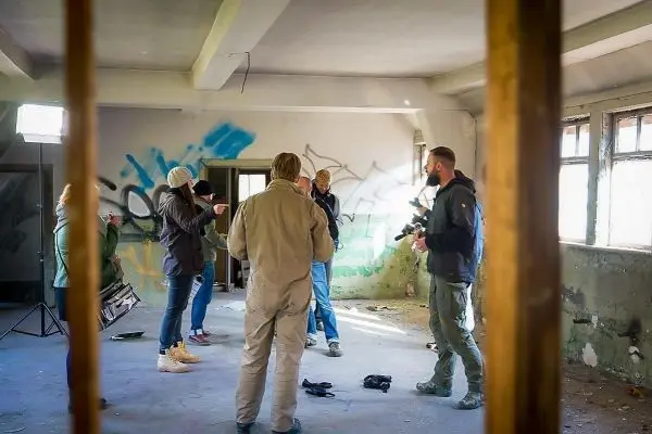Gruppe diskutiert in einem leerstehenden Raum mit Graffiti und Kameraequipment