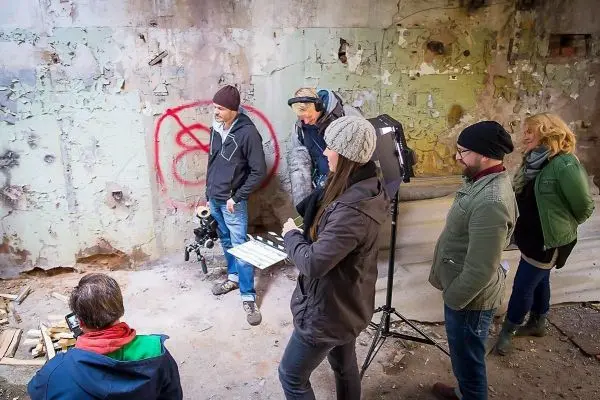 Gruppe diskutiert vor einer Wand mit Graffiti, Kamera und Beleuchtung sichtbar