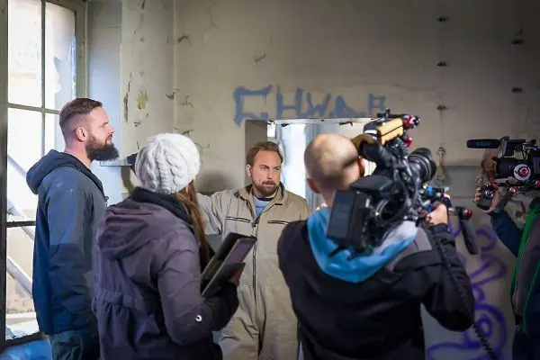 Gruppe von Personen in einem Raum mit Kamerateam und Mikrofon