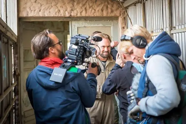 Kamerateam filmt in einem Innenraum mit mehreren Personen und Ausrüstung