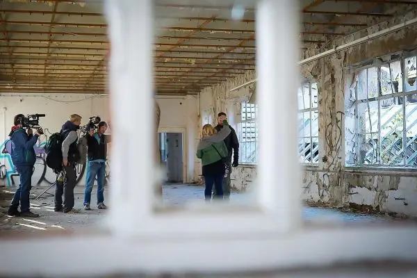 Kamerateam filmt Interview in einem verlassenen Raum mit beschädigten Wänden
