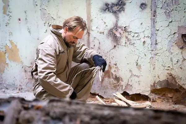 Mann bereitet Zunder aus Holzstücken in einem verlassenen Raum vor