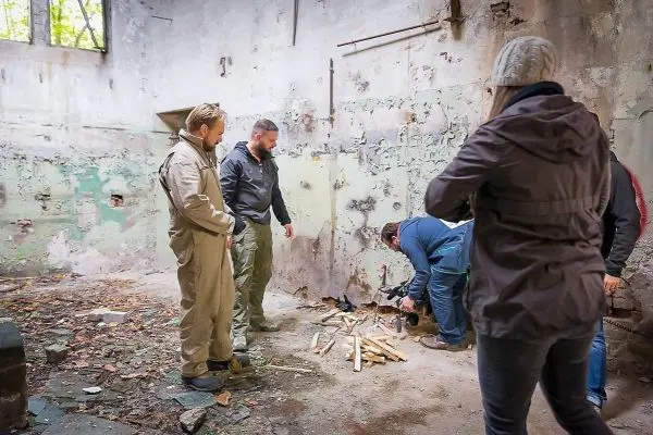 Personen stehen um einen Holzstapel in einem verlassenen Raum