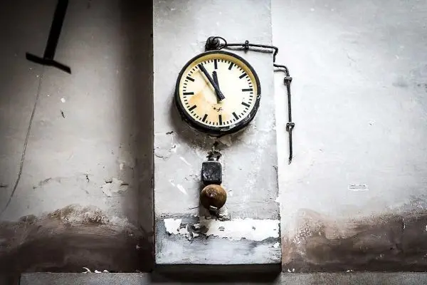 Wanduhr mit Zeigern und Glockenmechanismus an einer verputzten Wand