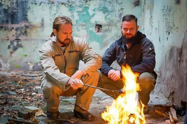 Zunder wird mit einem Stock in das Feuer gehalten