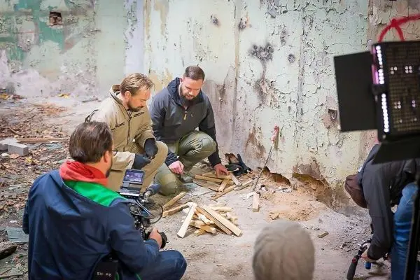 Zwei Personen bereiten Holz für ein Feuer in einem verlassenen Raum vor