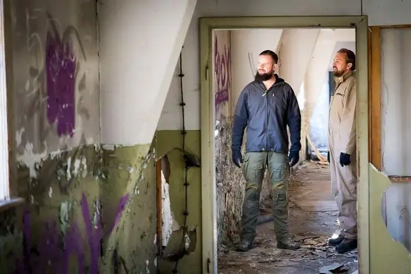 Zwei Personen stehen in einem verwahrlosten Raum mit Graffiti an den Wänden