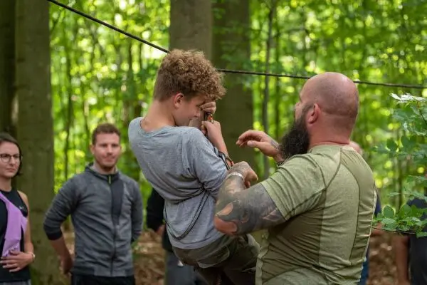 Ein Mann hilft einem Jungen beim Überqueren einer Seilbrücke im Wald