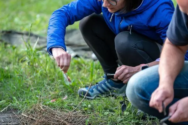 Feuerstahl erzeugt Funken auf Zunder in einer Graslandschaft