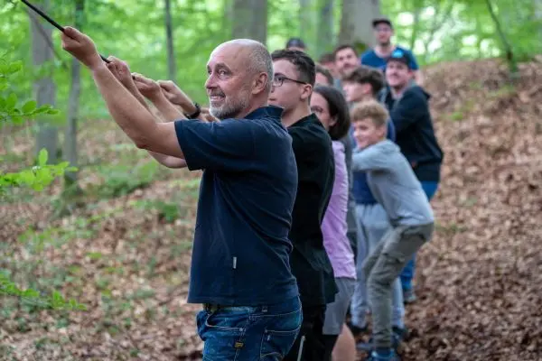 Gruppe zieht an einem Seil im Wald beim Überlebenstraining