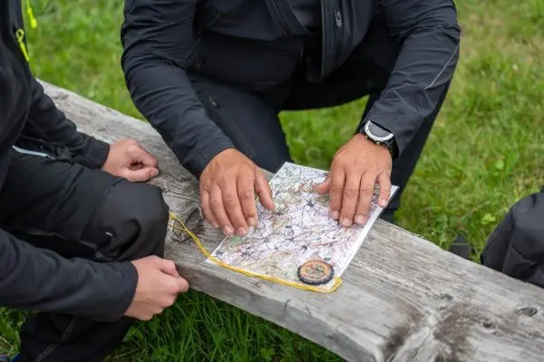 Hände zeigen auf eine Karte, während ein Kompass daneben liegt