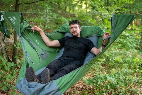 Hängematte zwischen Bäumen mit Person, die entspannt darin sitzt