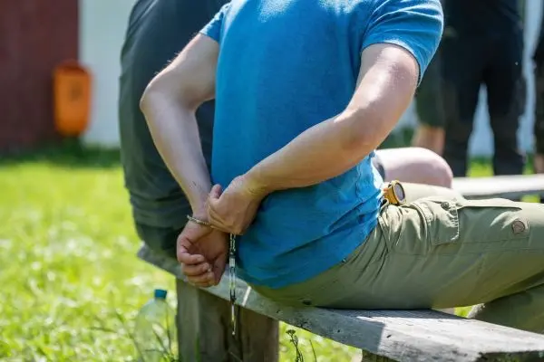 Handgelenke mit Handschellen hinter dem Rücken auf einer Bank abgelegt