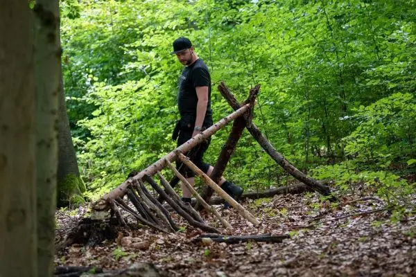 Holzkonstruktion aus Ästen wird im Wald inspiziert