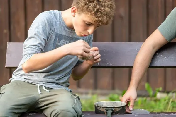 Junge bearbeitet Zunder in einer Schüssel auf einer Bank