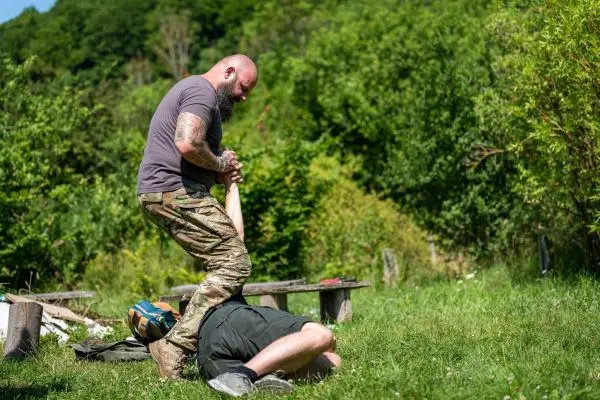 Kämpfer übt Kontrolle über einen am Boden liegenden Gegner mit einem Stock