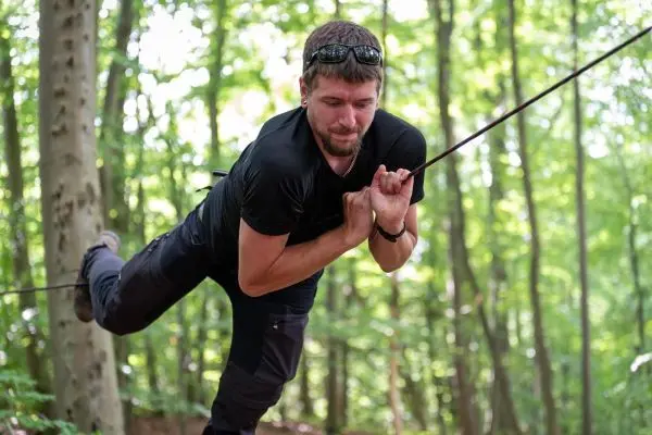Kletterer nutzt Seil für eine selbstgebaute Seilbrücke im Wald