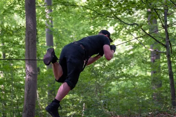 Körperliche Fortbewegung über eine selbstgebaute Seilbrücke im Wald