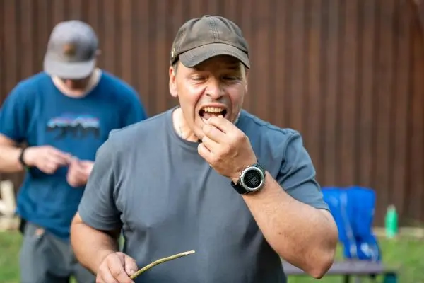 Mann beißt in einen Snack und hält einen Stock in der Hand