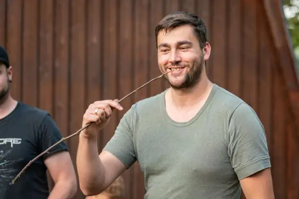 Mann hält einen Stock im Mund und lächelt