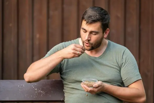 Mann isst aus einer Schüssel mit Samen und hält eine Hand zum Mund